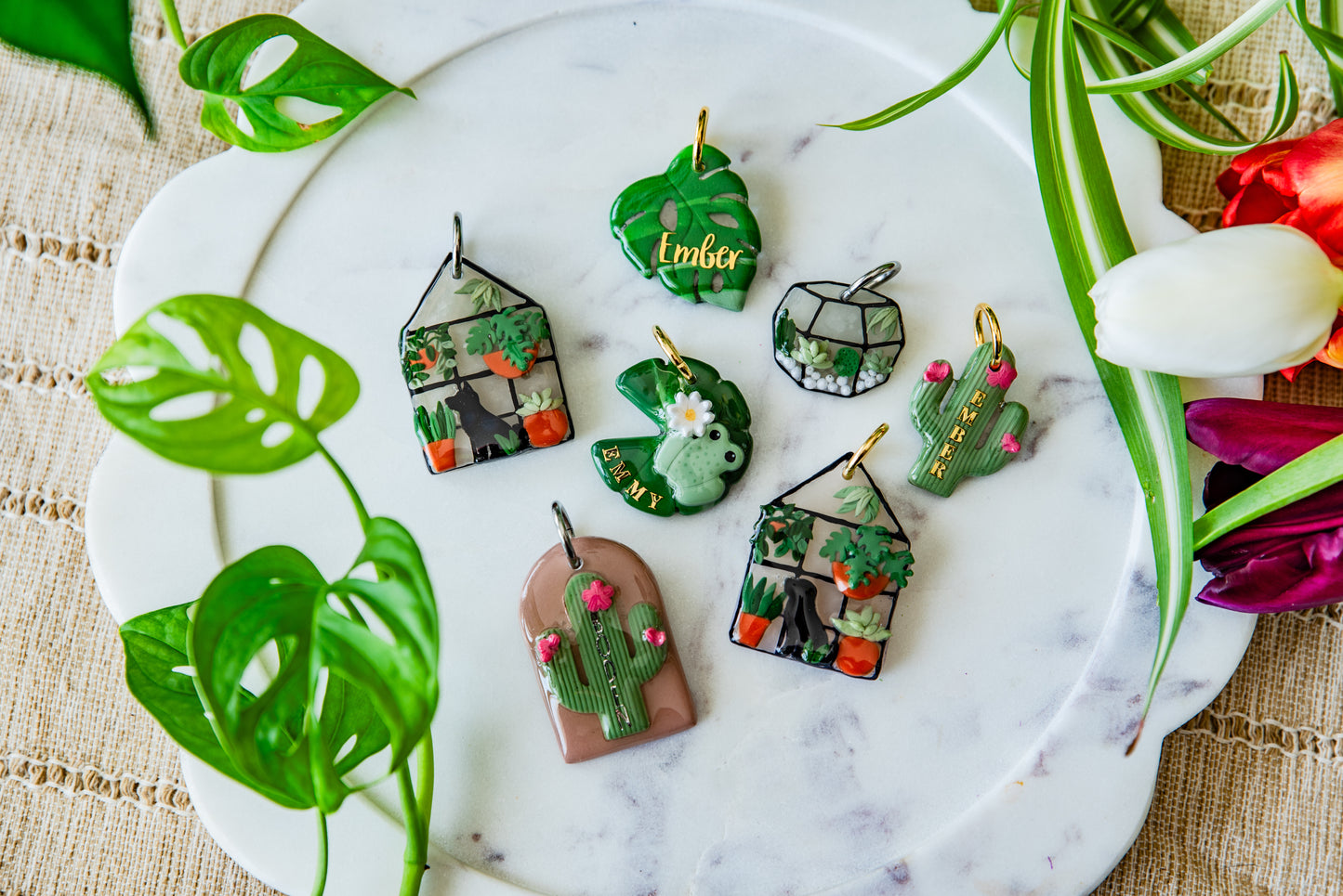 Set of small decorative items on a marble surface with plants and flowers around.