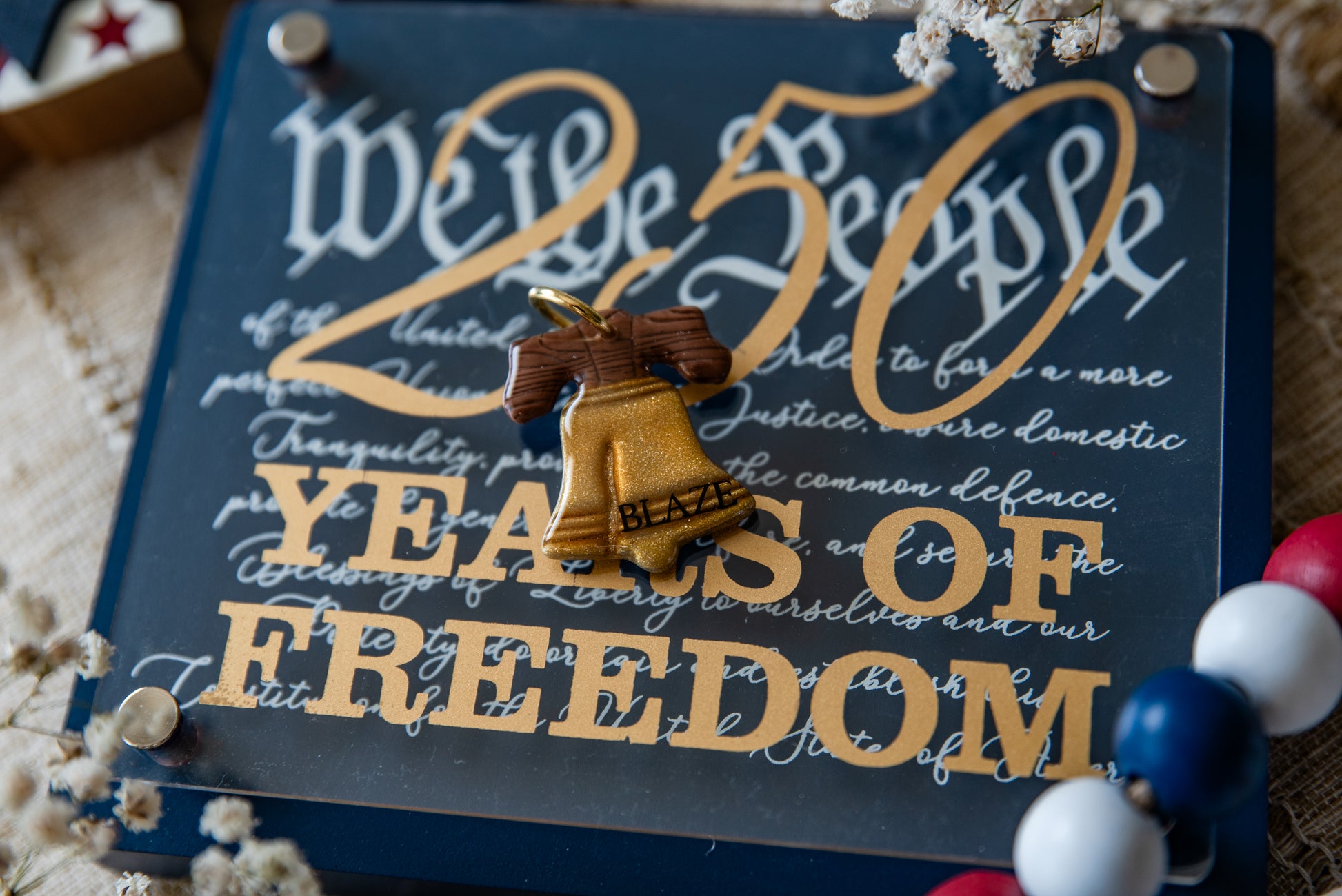 Decorative sign with '250 Years of Freedom' text and a bell emblem, surrounded by small decorative items.
